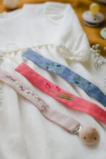zawieszki do smoczków handmade lniane łańcuszki z klipsem na smoczek haftowane w listki i kwiatuszki lilen